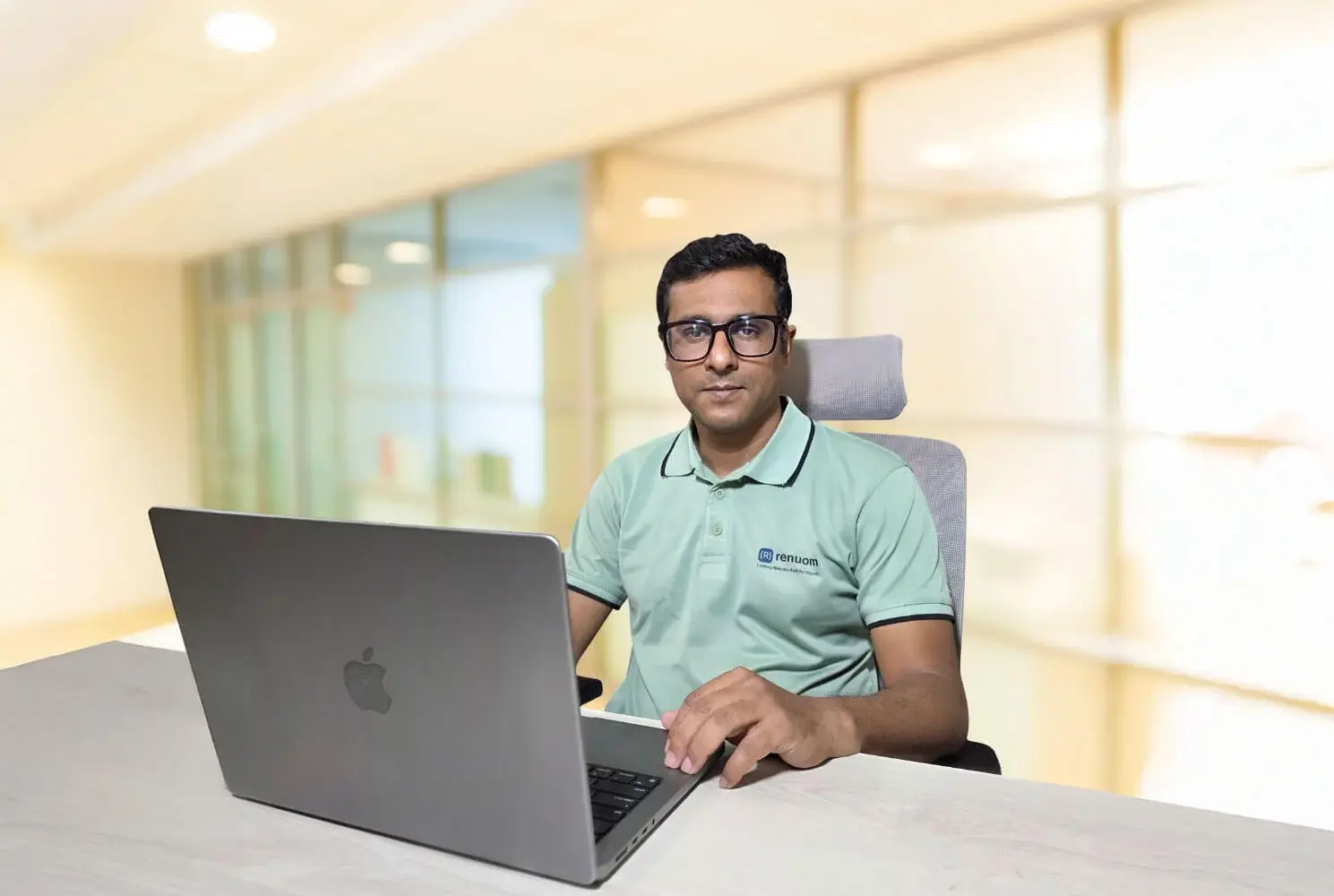 Portrait of Partha, an expert member of the Renuom digital team, sitting at his desk working on a laptop.